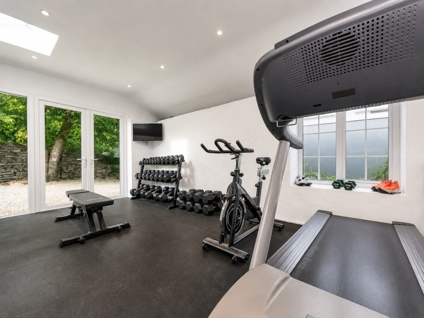 Wellness studio with treadmill, spin bike, dumbbells and bench